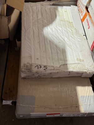 Des cartons contenant des matelas sont empilés les uns sur les autres dans un entrepôt