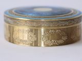 a gold box with a blue lid sitting on a white surface