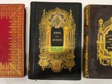 trois vieux livres sont alignés sur une surface blanche