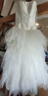a white dress hanging on a wooden rack in a room