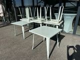 four white chairs and a table in front of a building