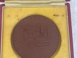 a brown medal in a red box on a white surface