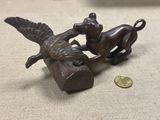 une statue en bronze représentant un chien et un oiseau posés sur un rocher