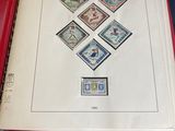 un livre rouge orné de timbres, posé sur une table