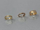 trois bagues en or et une bague posée sur un socle transparent