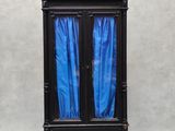 une armoire noire surmontée de rideaux bleus