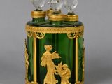 a green glass jar with a gold decoration on it