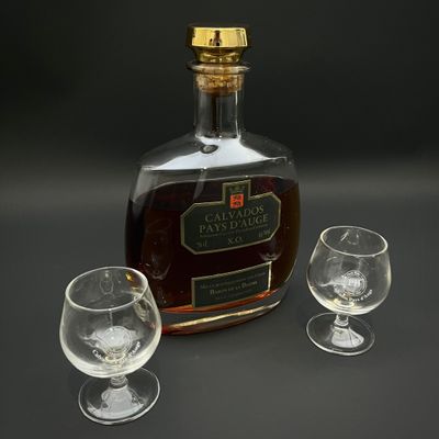 une bouteille d'alcool et deux verres posés sur une table