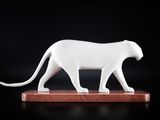 statue d'un chat blanc posée sur un socle en bois, sur fond noir