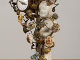 a statue of a woman holding a clock with flowers on it