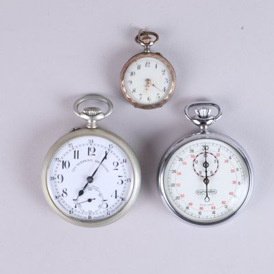two silver pocket watches sitting next to each other on a white surface