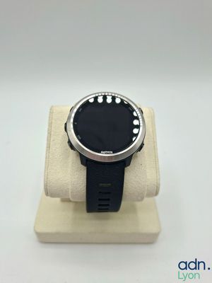 la montre est posée sur un socle, sur une surface blanche