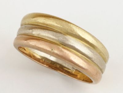 une bague composée de trois bandes dorées et argentées sur un fond blanc