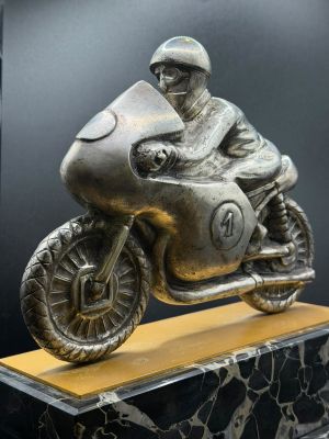 a statue of a man riding a motorcycle on a marble base