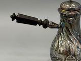 a silver coffee pot with a handle on a table