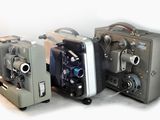 trois vieilles caméras de cinéma posées les unes à côté des autres sur une table
