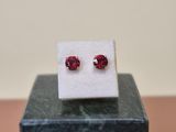 a close up of a pair of red ruby earrings on a marble block