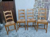 quatre chaises en bois sont alignées contre un mur en pierre