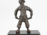une statue en bronze représentant un homme debout sur un socle noir