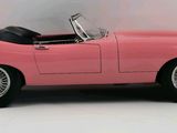 a pink toy car that is sitting on a white surface