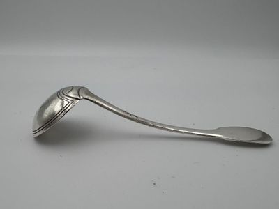 une cuillère en argent avec un manche de cuillère sur une surface blanche