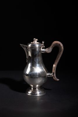 an antique silver coffee pot on a black background
