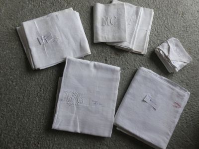 quatre serviettes blanches ornées de monogrammes brodés, posées sur une table