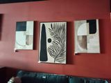 trois tableaux accrochés au mur au-dessus d'un canapé dans un salon