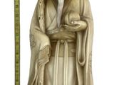 statue of an old man holding a bird and a ruler