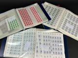 trois livres ouverts, sur lesquels sont apposés des timbres, posés sur une table