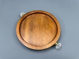 une assiette en bois avec une poignée, posée sur une surface grise