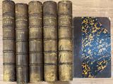 several old books sitting on top of a wooden table next to a book