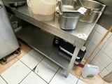 a metal table with a bucket and pans on it in a kitchen