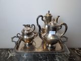 a silver tea set on a tray on a marble table