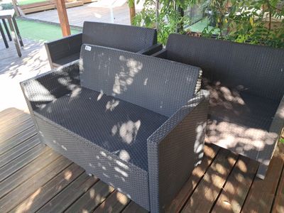 a black wicker couch sitting on a wooden deck