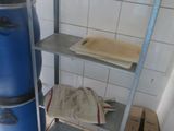 un seau bleu posé à côté d'une étagère métallique dans une salle de bains