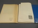 un livre ouvert posé sur une table, à côté d'un livre bleu