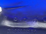 a blue glass bottle that is sitting on a white surface