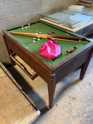 a pool table with two cues on it and a pink bag on the table