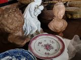 une table sur laquelle sont disposées de nombreuses assiettes et statues
