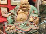 une statue représentant un Bouddha souriant, exposée dans une vitrine