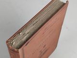 an old book with a brown cover sitting on top of a white table