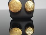 a close up of a pair of gold earrings on a black surface