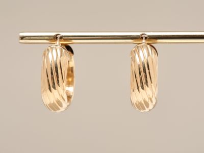 a close up of a pair of gold earrings hanging from a bar