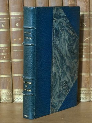 un livre bleu posé sur une table en bois, à côté d'une rangée de livres