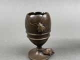 an image of a small bronze egg with a bird on it
