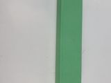 un livre vert posé sur une surface blanche, près d'un mur blanc