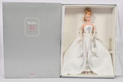 La poupée Barbie est dans une boîte, vêtue d'une robe blanche.