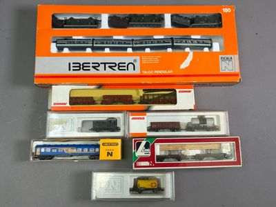 tout un tas de trains miniatures différents, rangés dans des boîtes sur la table