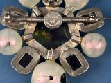 a silver brooch with pearls on it on a blue surface